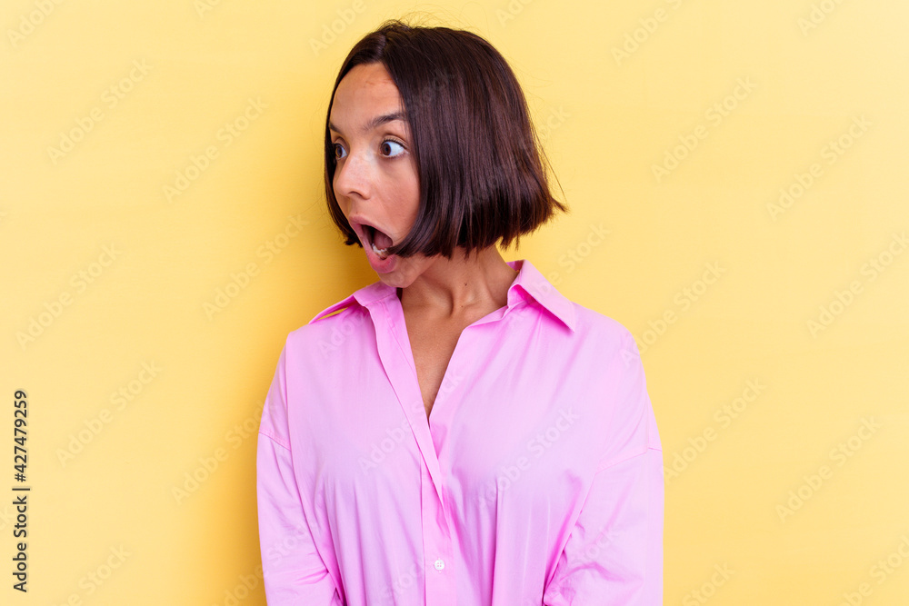 Fototapeta premium Young mixed race woman isolated on yellow background being shocked because of something she has seen.