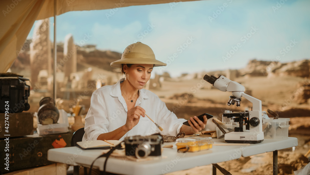 Archaeological Digging Site: Great Female Archaeologist Doing Research, Uses Smartphone to Share Discovery of Fossil Remains, Ancient Civilization Cultural Artifacts on Internet Social Media