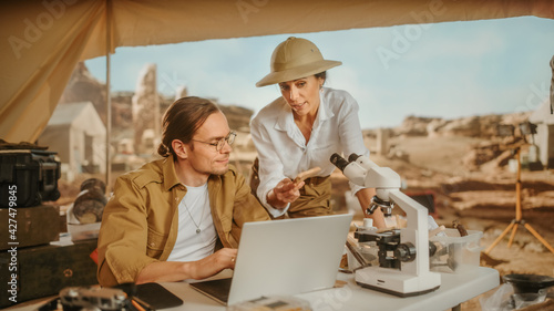 Archeological Digging Site  Two Great Archeologists Talk about Ancient Civilization  Cultural Artifacts  Fossil Remains  Use Laptop for Analysis. Diverse Team of Historians Research Excavation Site