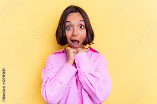 Young mixed race woman isolated on yellow background praying for luck, amazed and opening mouth looking to front.