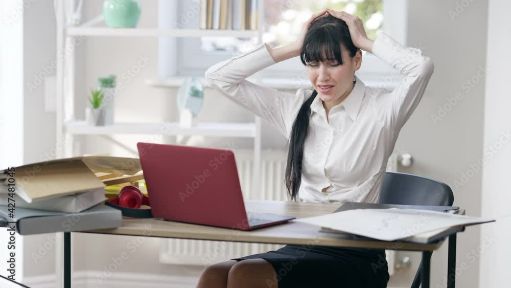 Portrait of overwhelmed young woman sitting in office holding head in hands screaming. Frustrated desperate Caucasian businesswoman having panic attack indoors. Burnout and business Portrait of overwhelmed young woman sitting in office holding head in hands screaming. Frustrated desperate Caucasian businesswoman having panic attack indoors. Burnout and business