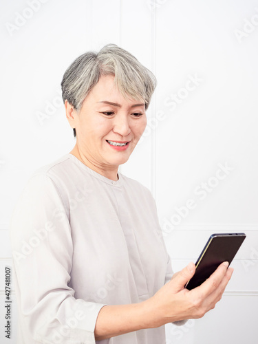 Happy mature senior asian woman holding smartphone using mobile online apps.