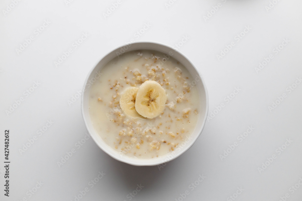 Bowl of oatmeal porridge with banana slices on white table. Healthy breakfast, diet food Bowl of oatmeal porridge with banana slices on white table. Healthy breakfast, diet food