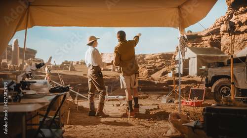 Φωτογραφία Archaeological Digging Site: Two Great Archeologists Work on Excavation Site, Look around, Use Map to Inspect Newly Discovered Ancient Civilization Architectural Site, Planning Work