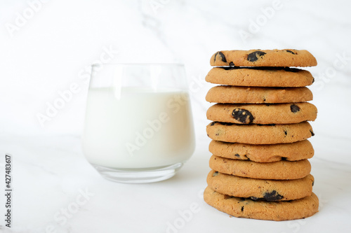 Stack of homemade chocolate chip cookies and glass of milk on marble background. Recipe of whaet bakery, biscuits with chocolate chips.