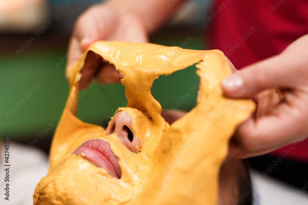 Fotografia do Stock beautician cleans remove alginate mask from the