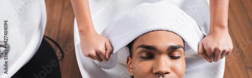 Top view of hairdresser holding towel near head of african american man, banner