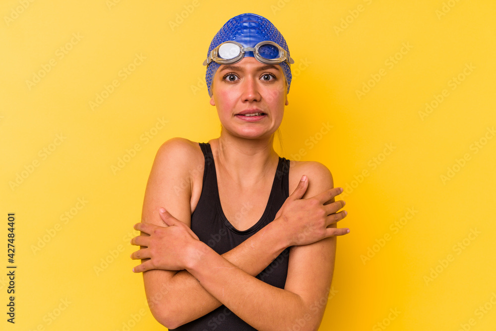Young swimmer venezuelan woman isolated on yellow background going cold due to low temperature or a sickness. Young swimmer venezuelan woman isolated on yellow background going cold due to low temperature or a sickness.
