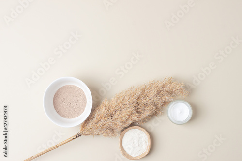 Natural background with skin care products and pampas dry grass on pastel beige. Flat lay, copy space
