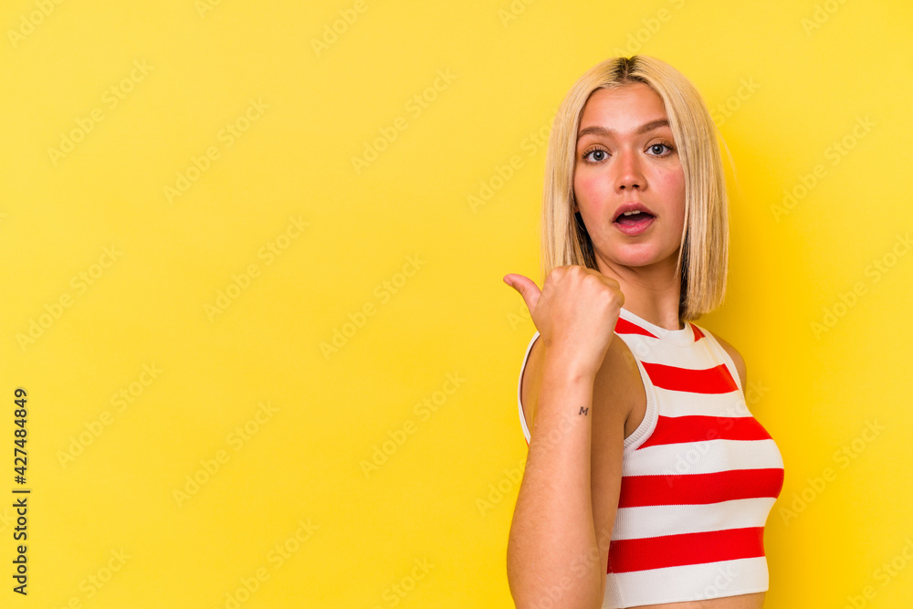 Young venezuelan woman isolated on yellow background points with thumb finger away, laughing and carefree. Young venezuelan woman isolated on yellow background points with thumb finger away, laughing and carefree.
