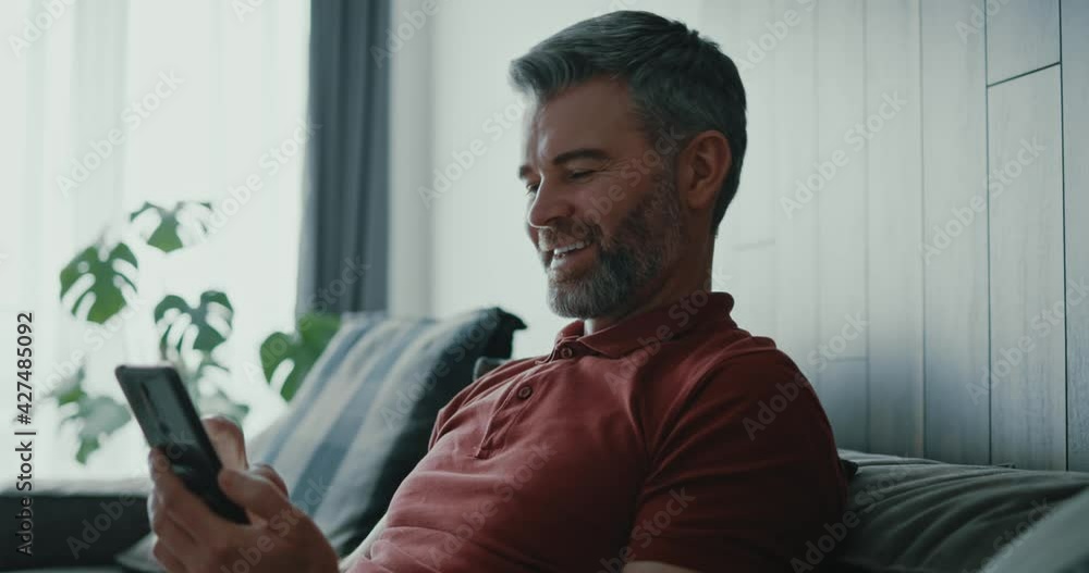 Positive caucasian grey-haired millennial adult male using mobile phone receiving fun messages answering friend typing on screen. Social media. Communications. Positive caucasian grey-haired millennial adult male using mobile phone receiving fun messages answering friend typing on screen. Social media. Communications.