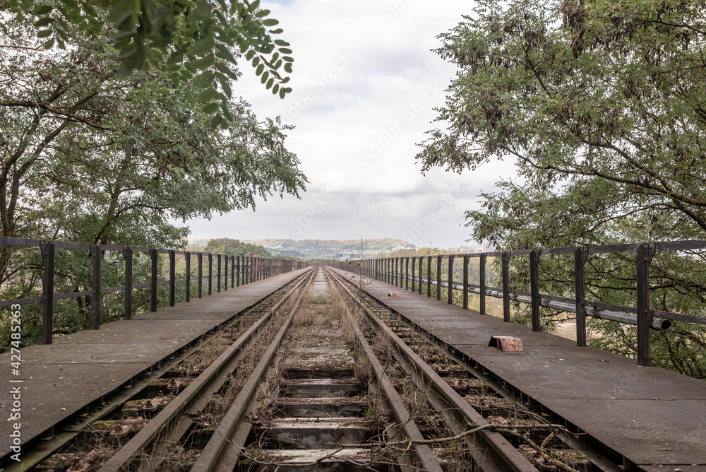 Railway track on a bridge, view of a cloudy sky, distancing perspective