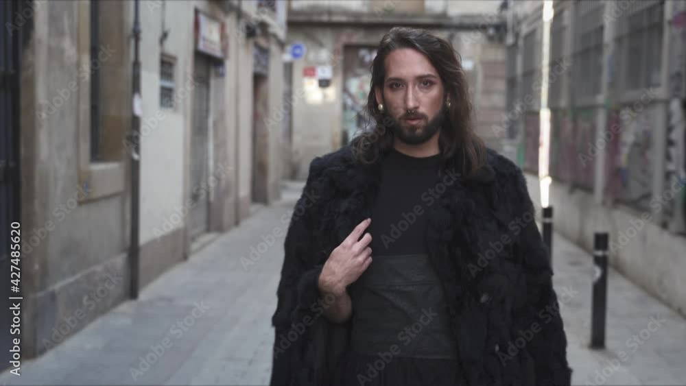 Transgender drag queen with beard, dark dress skirt and high heeled boots walking in the narrow streets of European city (Barcelona). Respect, sexual equality, diversity and pride for lgbt people Transgender drag queen with beard, dark dress skirt and high heeled boots walking in the narrow streets of European city (Barcelona). Respect, sexual equality, diversity and pride for lgbt people