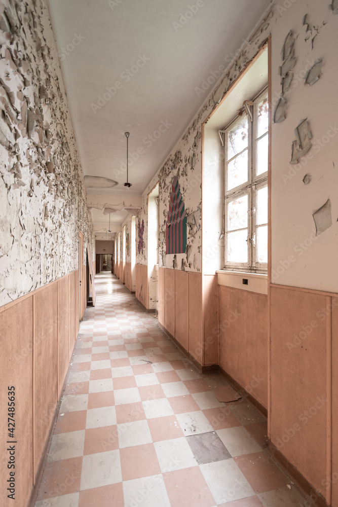Abandoned corridor with checkerboard pattern tiles in terracotta tones