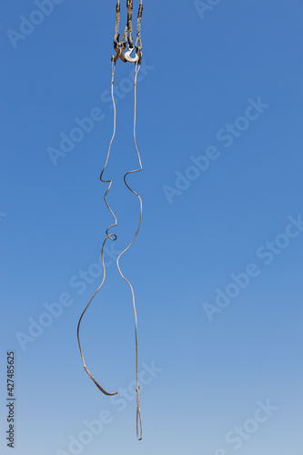 Free of cargo rope on hooks on the background of the blue sky. Vertical background of a construction sling, rope.