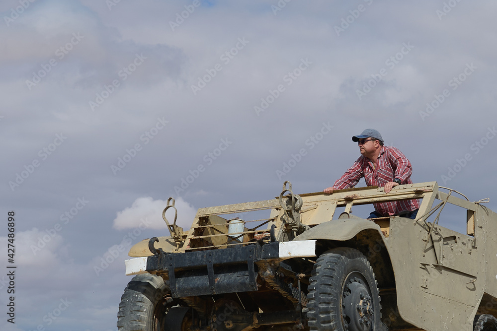 Fototapeta premium a man in a baseball cap and dark glasses in an old military vehicle