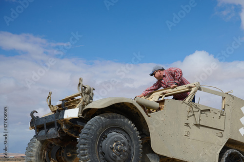 a man in a baseball cap and dark glasses in an old military vehicle photo