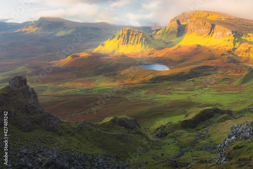 Vibrant golden light over epic mountain landscape of the rugged, contoured terrain of the Cleat and Dun Dubh at the Quiraing on the Isle of Skye, Scotland.
