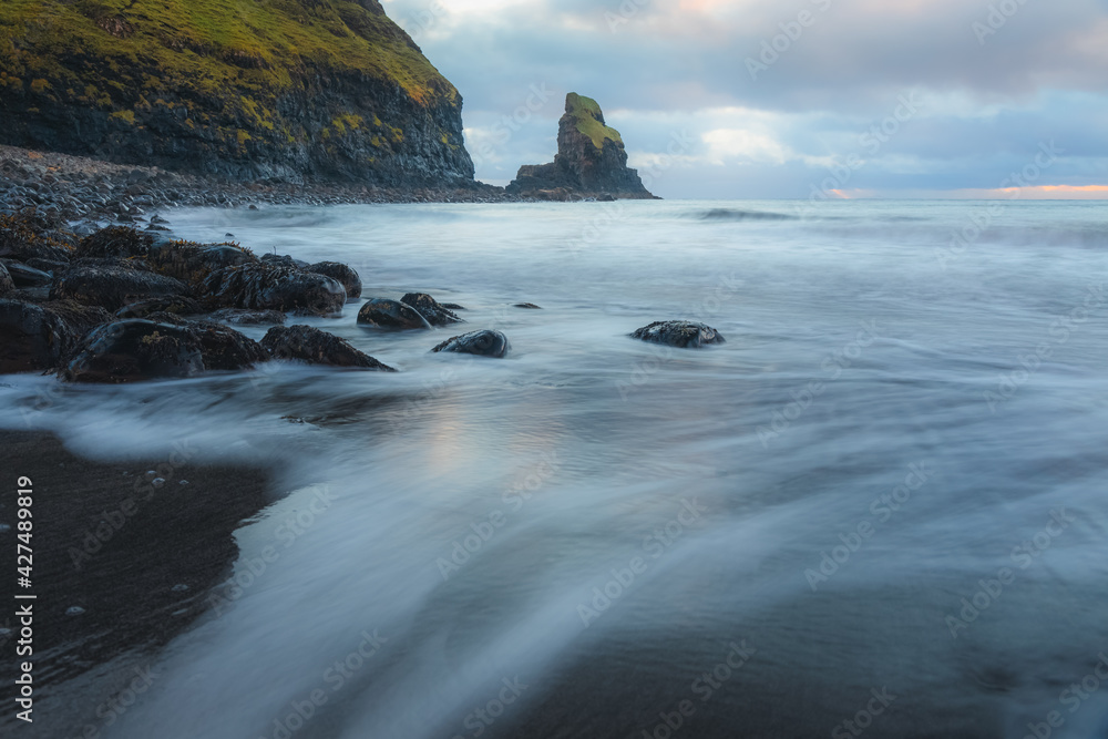 Moody seascape scenery and sea stack during sunrise or sunset at Talisker Bay Beach on the Isle of Skye, Scotland