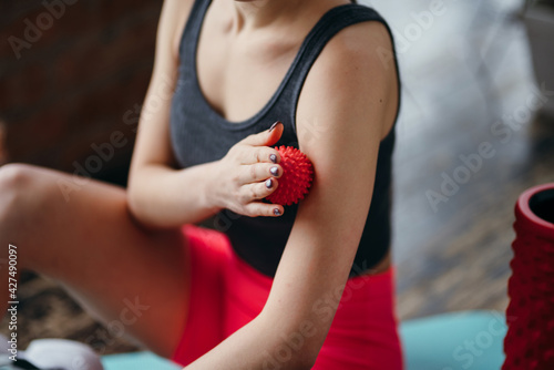 Close-up photo. Women's hands run a small massage ball over the arm, training and stretching the muscles in preparation for training