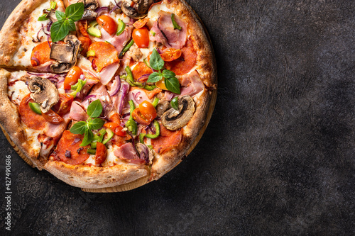 Italian pizza with pepperoni, mozzarella and mushrooms on a dark background, copy space, horizontal orientation, flat lay, close-up