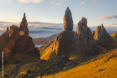Atmospheric golden sunrise light over the dramatic, colourful landscape of the iconic rock pinnacle Old Man of Storr on the Isle of Skye in the Scottish Highlands.