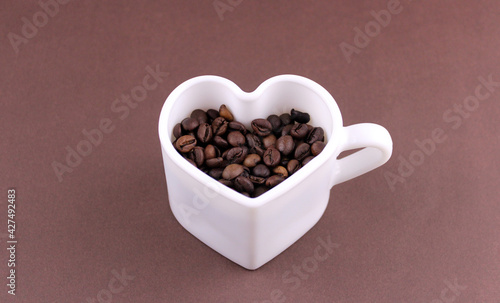 White heart shaped mug with roasted coffee beans © Valeria F