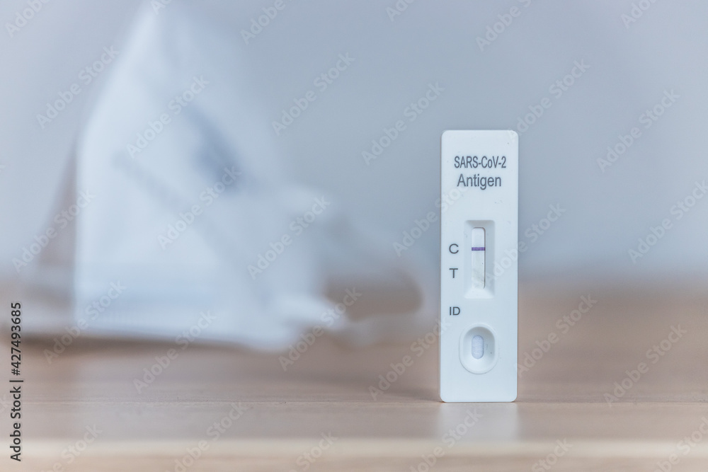 Express corona test at home: Close up of a negative covid antigen test, ffp2 mask in background Express corona test at home: Close up of a negative covid antigen test, ffp2 mask in background