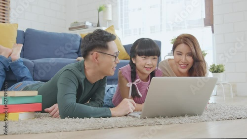 Happy Asian family using computer laptop together on sofa at home living room.