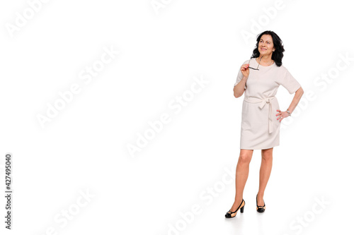 Full length portrait of a confident woman businessman, dressed in a light dress and shoes. He holds glasses in his hand. White background.Copy space