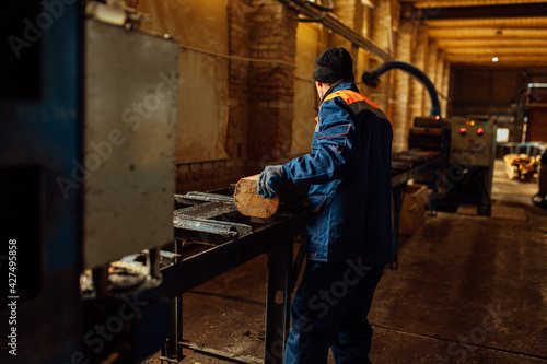 wooden board on the conveyor. people work on an automated sawmill. industrial enterprise for wood processing. a worker carries a board for sawing