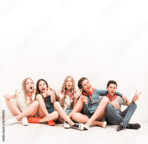 cute smiling tenagers sitting on the floor with legs crossed