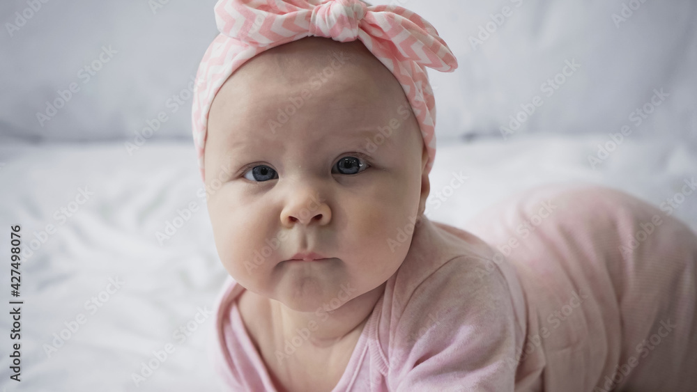 curious infant baby in headband with bow looking at camera. curious infant baby in headband with bow looking at camera.
