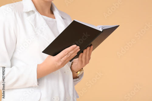 Young woman with book on color background, closeup