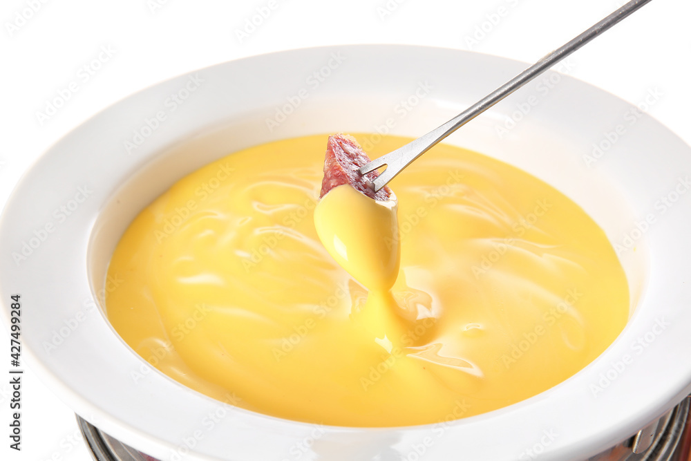 Stick with sausage dipped into cheese fondue on white background Stick with sausage dipped into cheese fondue on white background
