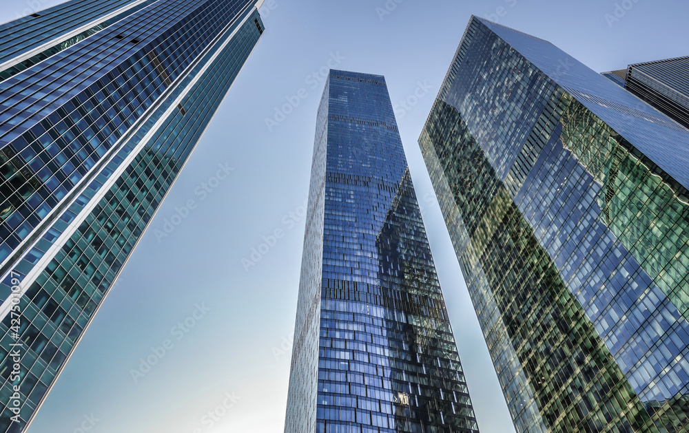 Three nearby financial centers skyscrapers in one shot. An image from a low angle. The background is a blue and cloudless sky.