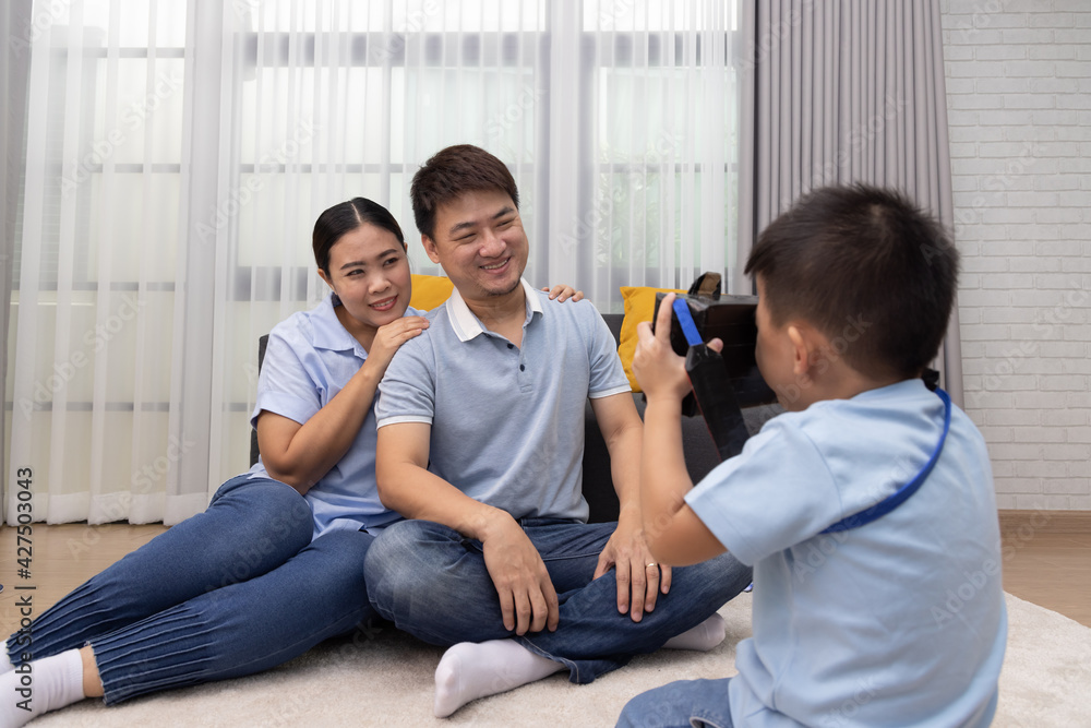 Portrait of happy Asian couple take a pictures by son in living room at home, Little boy photographer and Family relax lifestyle concept Portrait of happy Asian couple take a pictures by son in living room at home, Little boy photographer and Family relax lifestyle concept