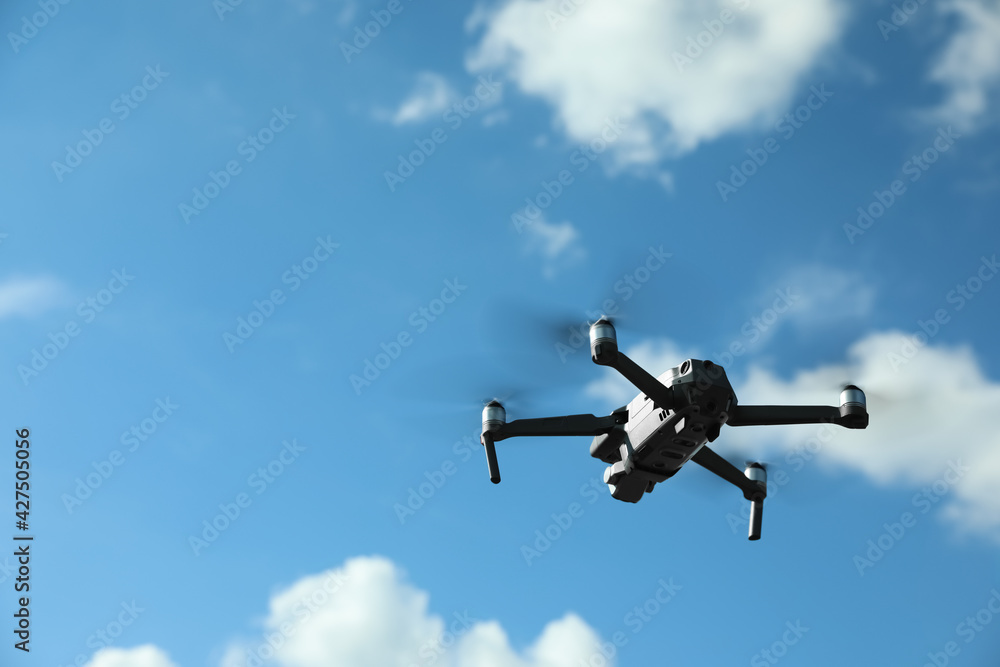 Modern drone with camera flying in sky on sunny day Modern drone with camera flying in sky on sunny day