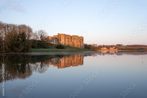 View of Carew castle in Pembrokeshire, Wales, UK with reflections on the water of the moat