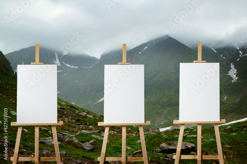 Wooden easels with blank canvases in mountains photo