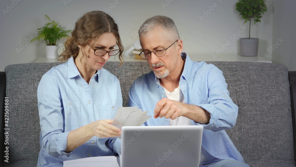 A married couple discusses financial expenses on a laptop. A married couple discusses financial expenses on a laptop.