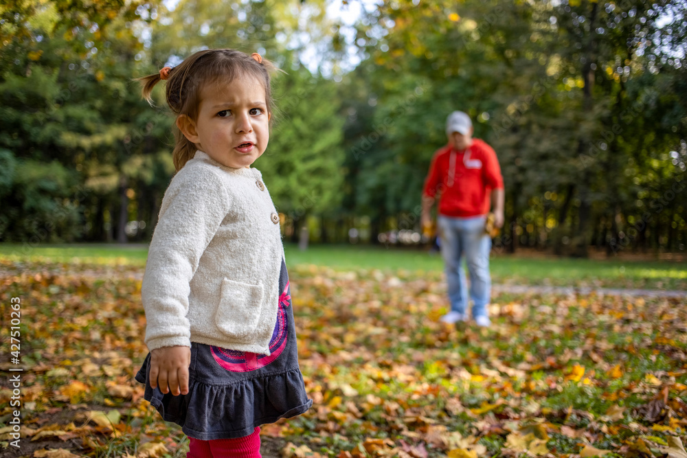 disgruntled child in the park with dad. angry girl in the park looks at the camera. father and daughter Toddler walk in the park disgruntled child in the park with dad. angry girl in the park looks at the camera. father and daughter Toddler walk in the park