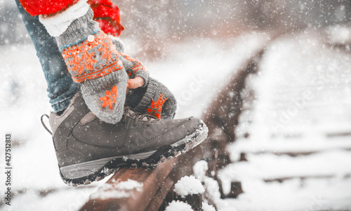 Girl tying shoe laces on the rails in winter