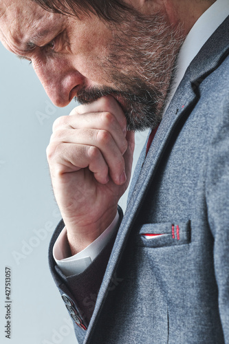Pensive businessman overburdened with thoughts thinking with hand on chin