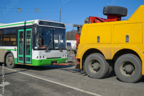 A tractor is towing a faulty bus on a suburban highway....
