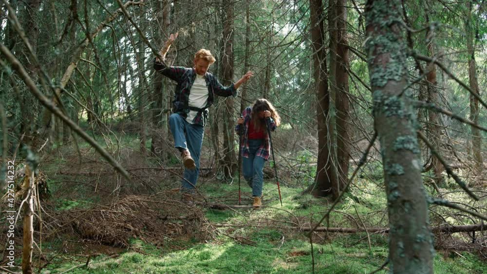 Man and woman hiking in fairytale forest. Smiling hikers walking in green woods Man and woman hiking in fairytale forest. Smiling hikers walking in green woods