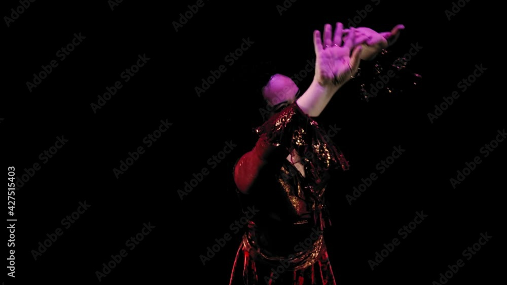 cheerful gypsy woman with long black hair in a red lush dress dances on a black background. Medium plan cheerful gypsy woman with long black hair in a red lush dress dances on a black background. Medium plan