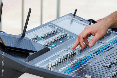 mixing console and a man's hand reaches for the keys