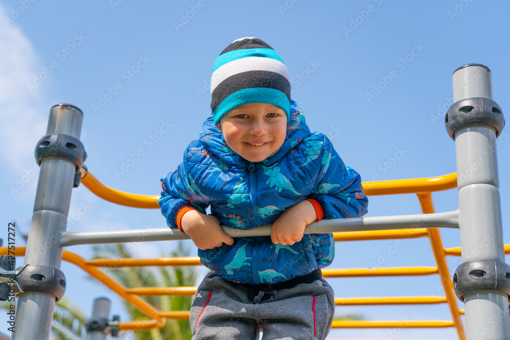 A child from a horizontal bar looks down to the camera