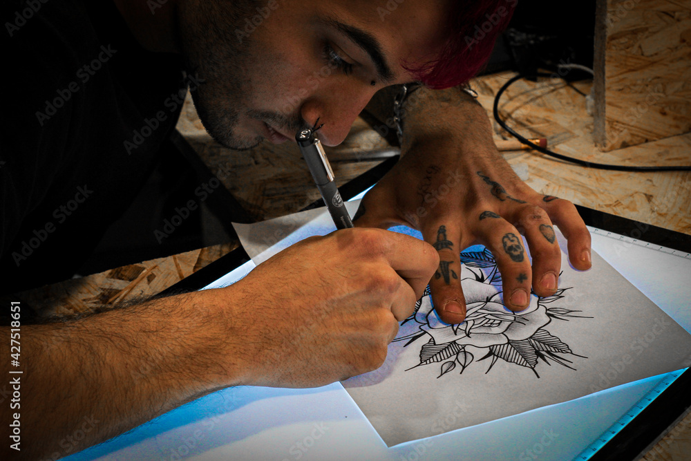 Obraz premium A tattoo artist sketching a tattoo in his tattoo studio.